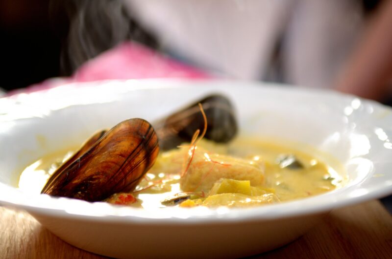 Fisksoppa med lax, havskatt, färska musslor, smaksatt med saffran, curry, cayenne och ett stänk chili serveras med hembakad baguette